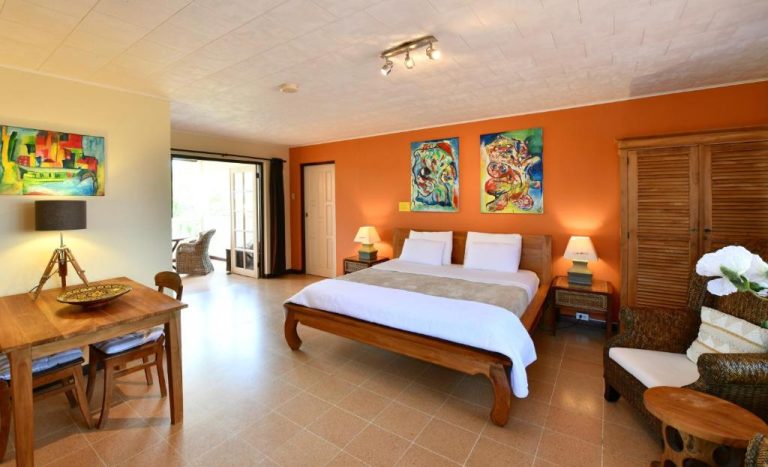 Habitación doble con decoración tropical y pared naranja en Wonders Boutique Hotel