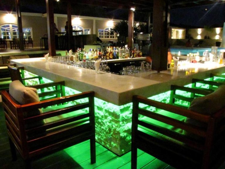 Bar exterior con iluminación LED verde y amplia selección de bebidas en el Trupial Hotel & Casino