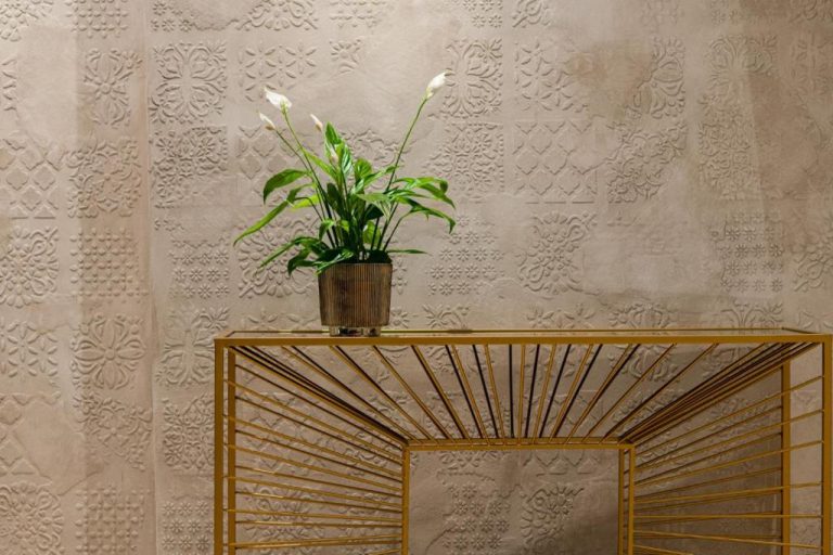 Detalle decorativo con planta tropical y mesa dorada en el lobby del Bayview Hotel by ST Hotels