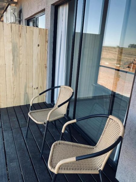 Terraza exterior con sillas de mimbre y vistas al paisaje desértico en PLC Hotel Centenario