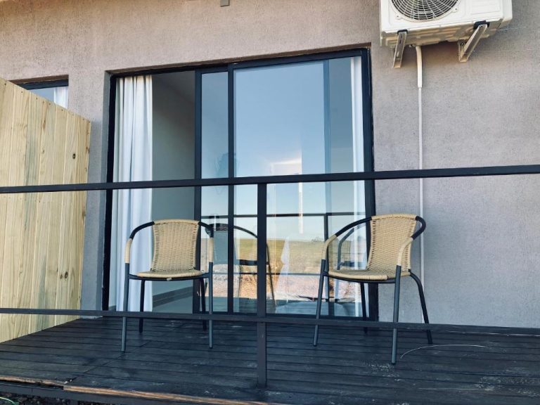 Terraza exterior con sillas de mimbre y puerta corredera de cristal en PLC Hotel Centenario