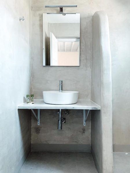 Baño moderno con lavabo sobre encimera y paredes de microcemento en Fabrica Sunset Apartments