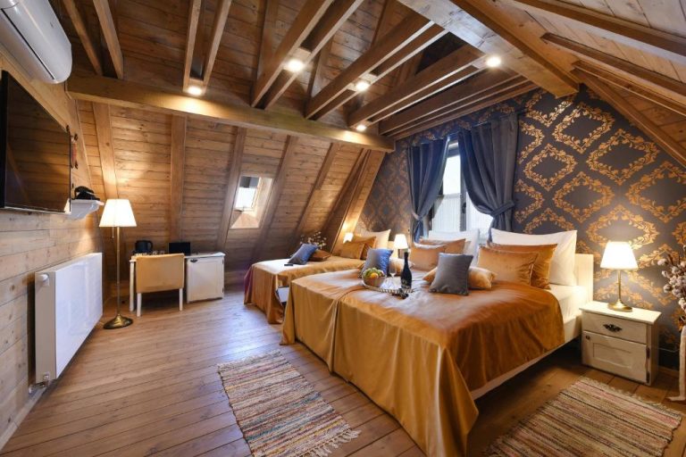 Habitación abuhardillada de lujo con vigas de madera y decoración dorada en Lakeside Hotel Plitvice