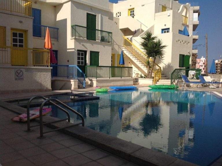 Piscina exterior con flotadores y sombrillas de colores en Sea N Lake View Hotel Apartments