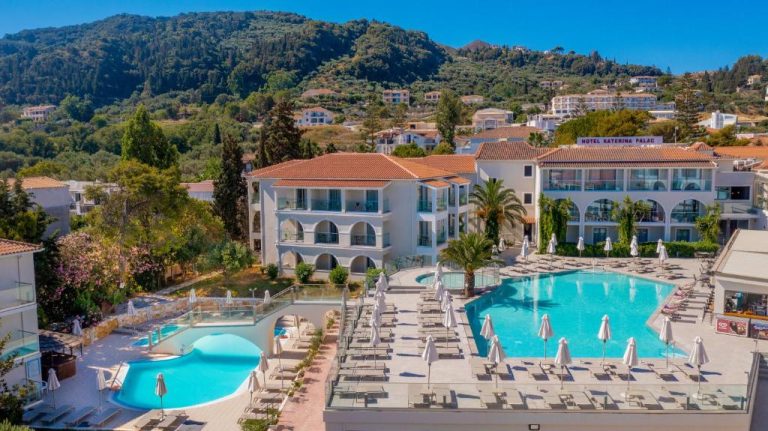 Vista aérea de las piscinas exteriores con tumbonas y sombrillas del Katerina Palace Hotel en Grecia