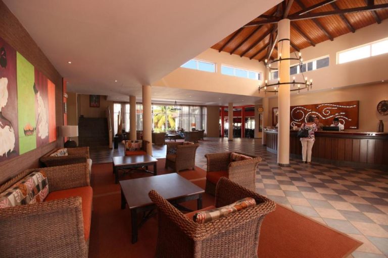 Amplio lobby con recepción y zona de descanso con sillones de ratán en el Pestana Trópico
