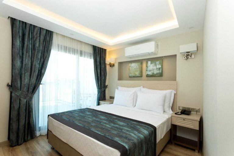 Habitación doble con cama grande y cortinas verdes en Güllük Yalı Boutique Otel