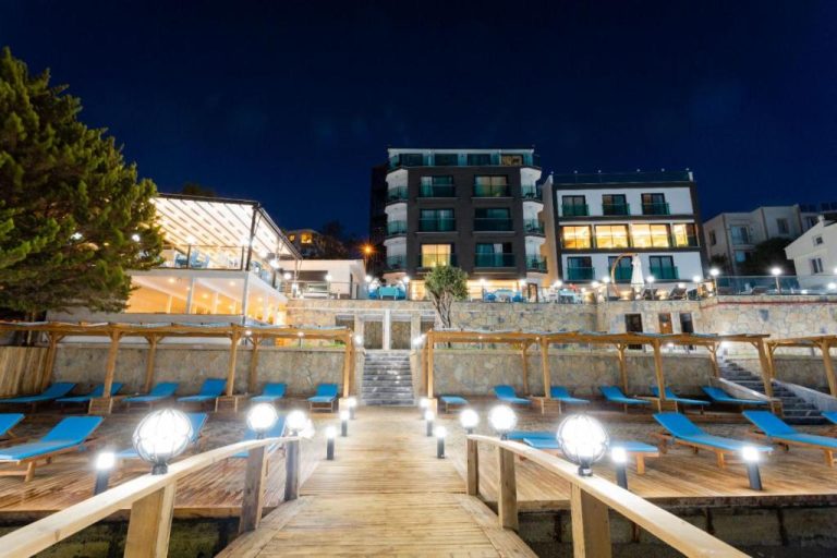 Terraza frente al mar con tumbonas azules iluminada de noche en Güllük Yalı Boutique Otel