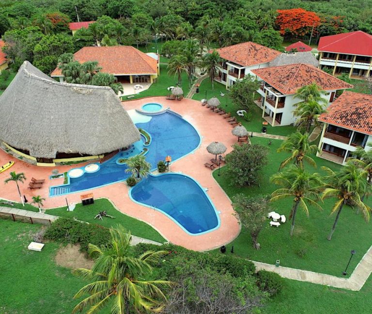 Vista aérea de las piscinas exteriores y bungalow de playa del Nandel Beach Resort rodeado de palmeras