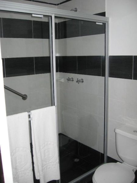 Baño moderno con ducha acristalada y azulejos en blanco y negro del AW Hotel Sport