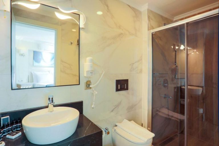 Baño de mármol con ducha de cristal y lavabo oval en Güllük Yalı Boutique Otel