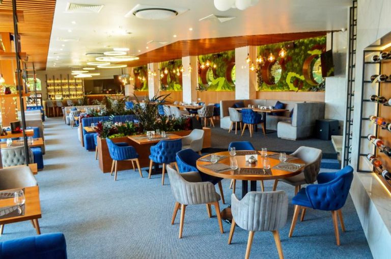 Elegante restaurante interior del Park Hotel Stara Zagora con sillas azules y decoración vegetal