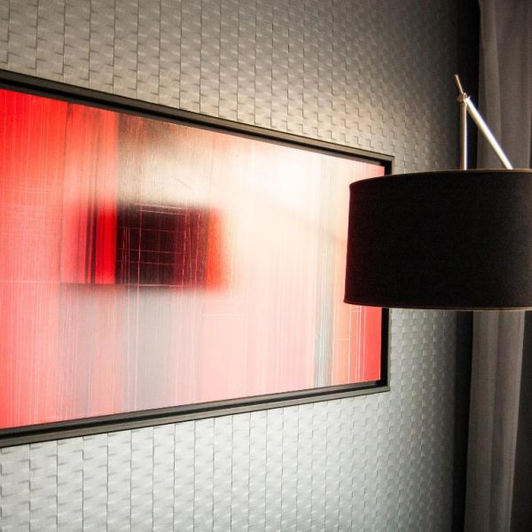 Detalle de habitación con cuadro abstracto en rojo y lámpara de pie negra en Fierro Hotel Buenos Aires