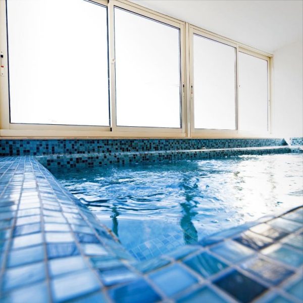 Piscina interior con azulejos azules y ventanales del Bayview Hotel by ST Hotels
