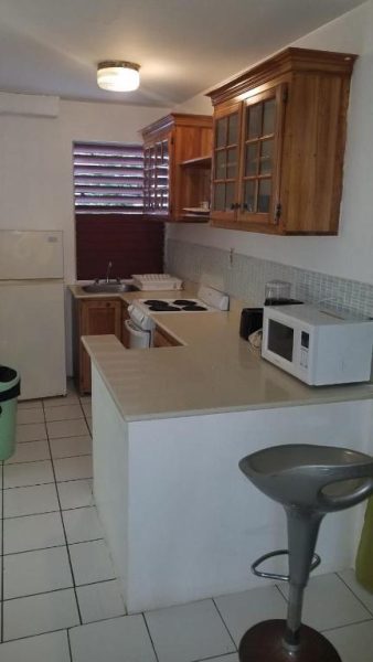 Cocina equipada con microondas, estufa y barra desayunadora en Negril Beach Club Condos