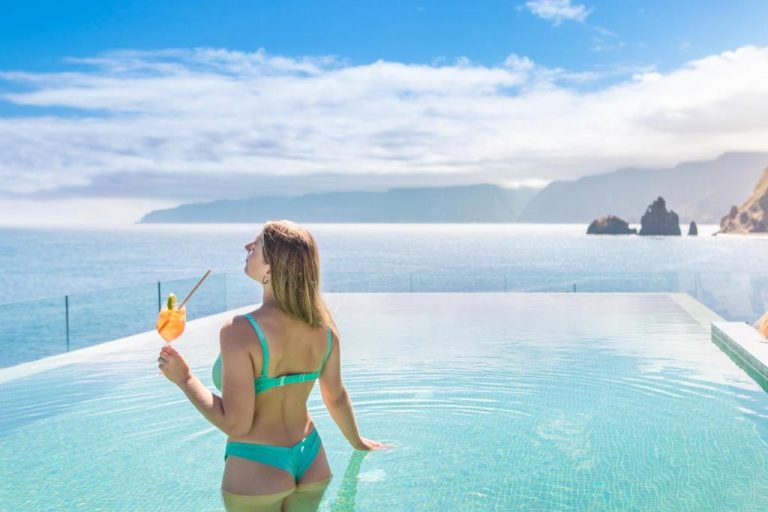 Mujer disfrutando de la piscina infinita con vistas al mar y acantilados en Aqua Natura Bay