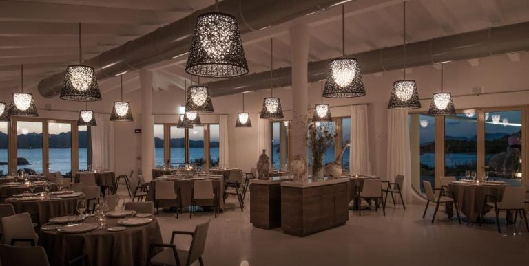 Restaurante elegante con lámparas decorativas y vistas al mar al atardecer en Cala Cuncheddi VRetreats