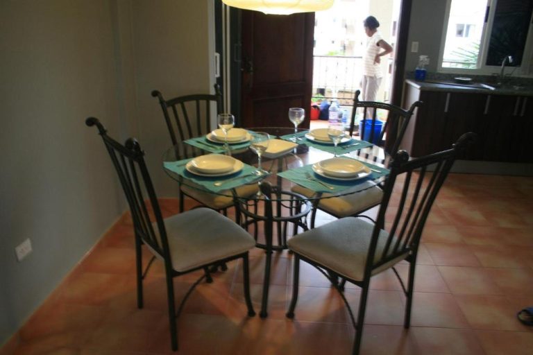 Comedor elegante con mesa de cristal y sillas de hierro forjado en el hotel Bavaro Green