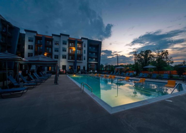 Piscina exterior iluminada al atardecer del Apart Hotel at Chinatown con tumbonas y sombrillas