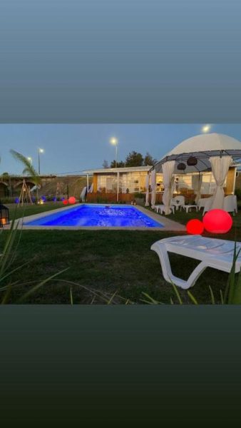 Piscina iluminada con gazebo y esferas decorativas del Hotel Terrazas del Río Negro al atardecer