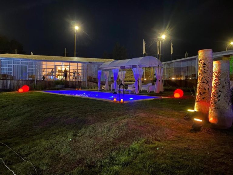 Piscina exterior iluminada de noche con gazebo y jardín del Hotel Terrazas del Río Negro