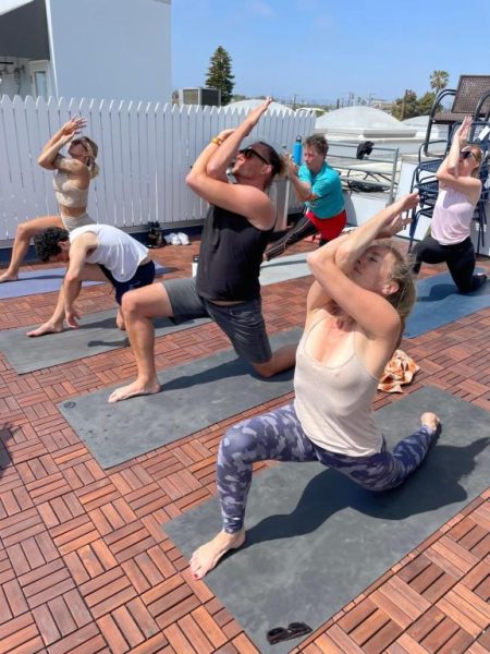 Clase de yoga al aire libre en la terraza del hotel STAY OPEN Venice Beach con vistas al cielo