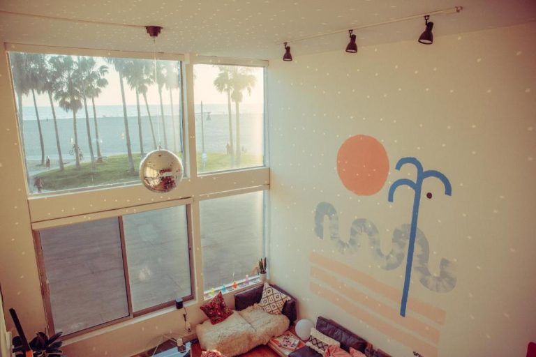 Sala con mural decorativo y bola de discoteca en Stay Open Venice Beach con vistas a las palmeras