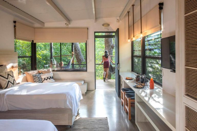 Habitación con camas dobles y terraza con hamacas rodeada de naturaleza en Rio Perdido Hotel