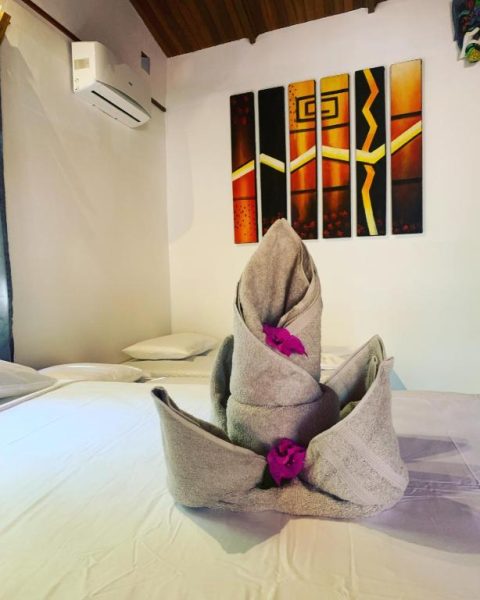 Habitación del Beach Front Bahia con toallas decoradas en forma floral y arte colorido en la pared