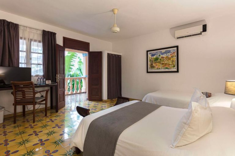 Habitación doble con balcón y suelo hidráulico del Hotel Villa Colonial con aire acondicionado