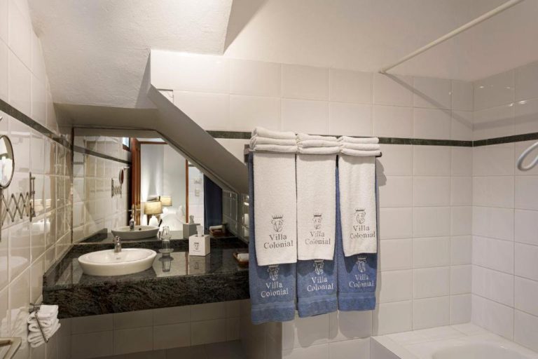 Baño elegante con lavabo de mármol y toallas bordadas del Hotel Villa Colonial