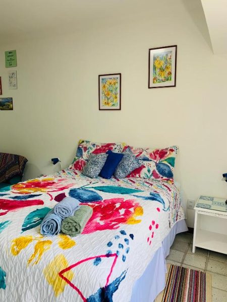 Habitación con cama matrimonial y ropa de cama colorida en Studio perto do Cristo, barrio Ondina