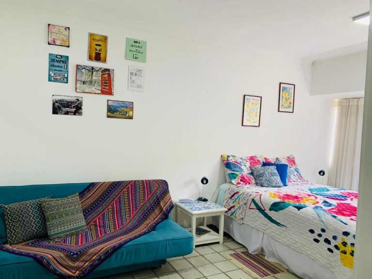 Habitación con cama doble y sofá azul del Studio perto do Cristo, cerca del circuito Ondina