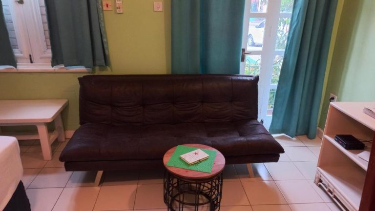 Sala de estar con sofá de cuero marrón y mesa auxiliar en Beach Studio 9