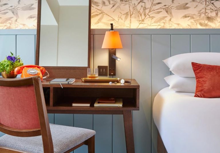 Habitación elegante con escritorio de madera, lámpara naranja y cama doble en Hodson Bay Hotel