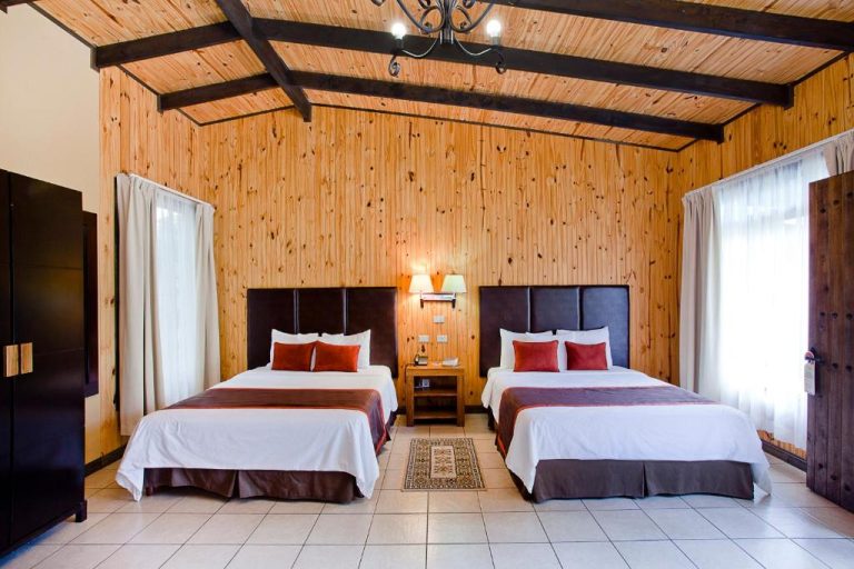 Habitación doble con paredes de madera y techo de vigas en Savegre Hotel Natural Reserve & Spa