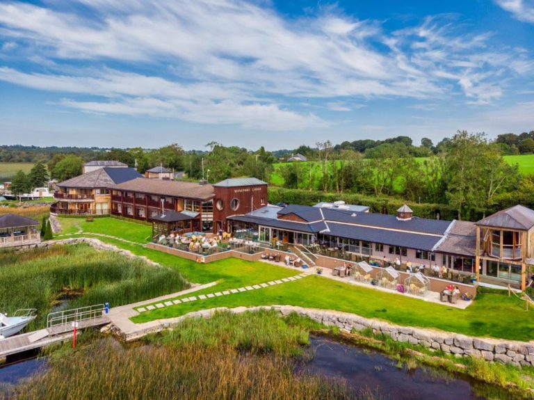 Vista aérea del Wineport Lodge con terraza exterior, jardines verdes y acceso privado al lago en Irlanda