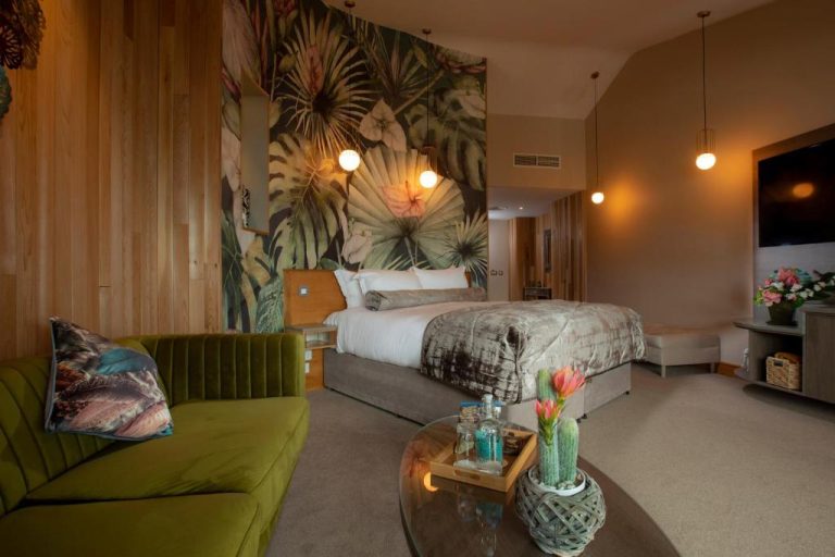 Habitación deluxe con mural tropical, sofá verde y cama doble en Wineport Lodge