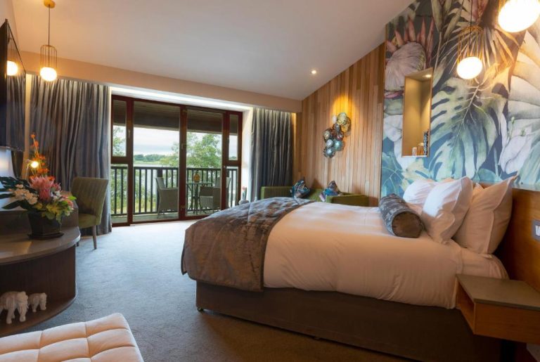 Habitación superior con cama doble, decoración tropical y balcón con vistas al lago en Wineport Lodge