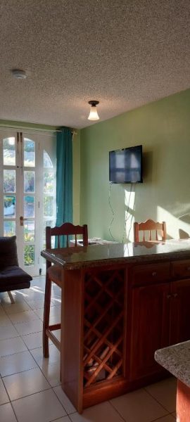 Cocina americana con barra de madera y sala de estar con TV en Beach Studio 9