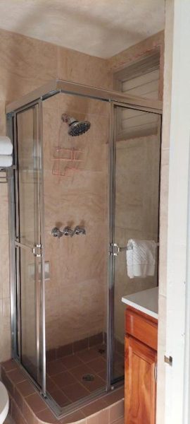 Ducha independiente con mampara de cristal y azulejos beige en el baño privado de Beach Studio 9