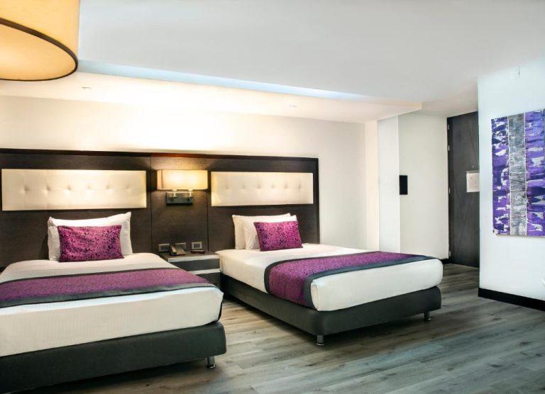 Habitación doble con dos camas y decoración en tonos morados en Hotel City Bog Expo Museo