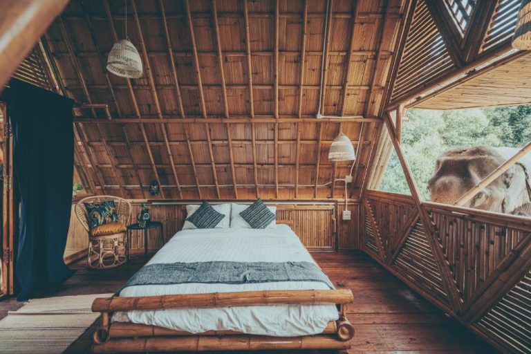 Habitación de bambú con cama doble y elefante asomado a la ventana en Chai Lai Orchid