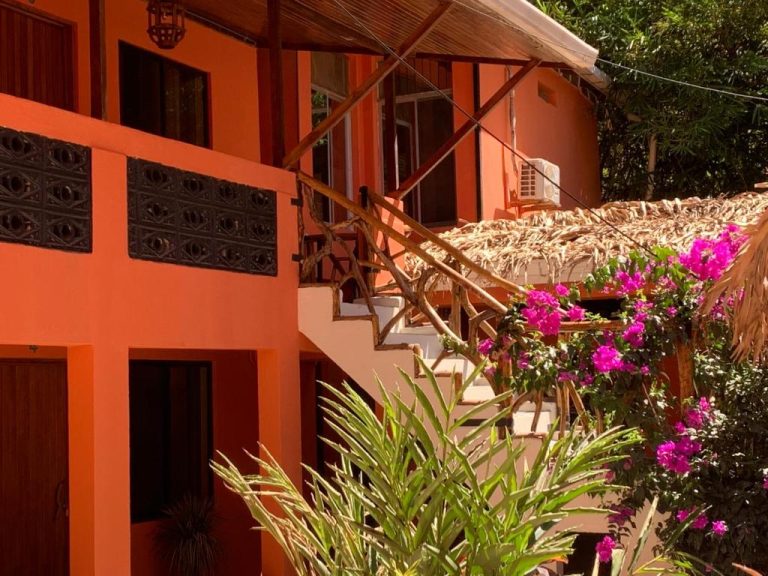 Fachada naranja con escaleras de bambú y buganvilias rosas del hotel Beach Front Bahia