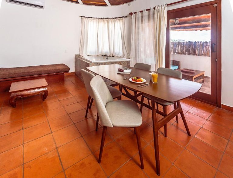 Comedor con mesa de madera, sillas y jacuzzi interior en Fabiola Condo Hotel con acceso a terraza