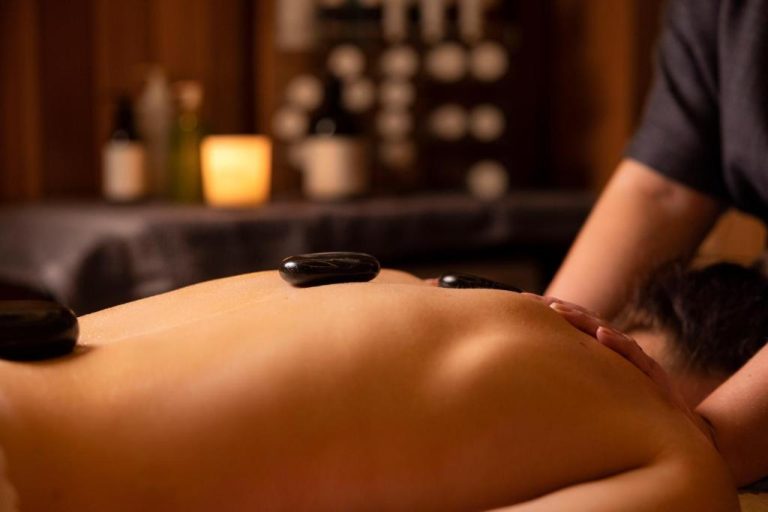 Tratamiento de masaje con piedras calientes en el spa del Wineport Lodge, ambiente relajante con velas