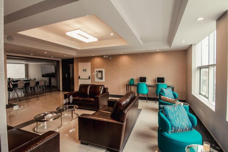 Sala de estar moderna con sofás de cuero y sillones turquesa en el lobby del Hotel Diamond Lima