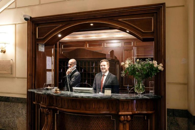 Recepción clásica de madera con dos recepcionistas atentos en el Grand Hotel Wagner