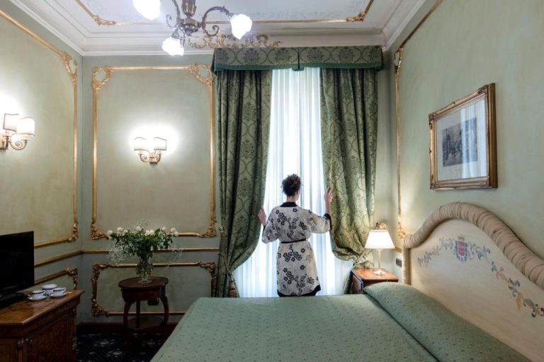 Habitación clásica con cortinas verdes y decoración dorada del Grand Hotel Wagner en Palermo