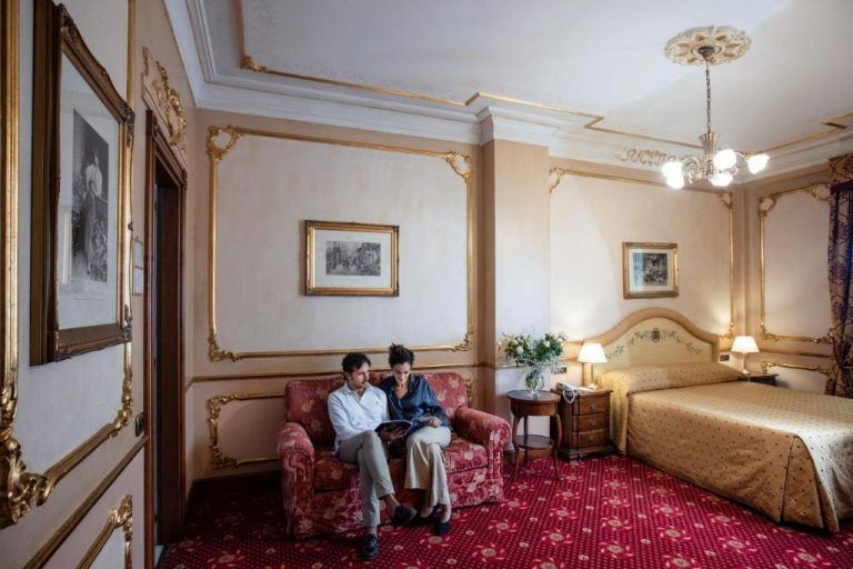 Pareja descansando en lujosa suite clásica con decoración dorada del Grand Hotel Wagner